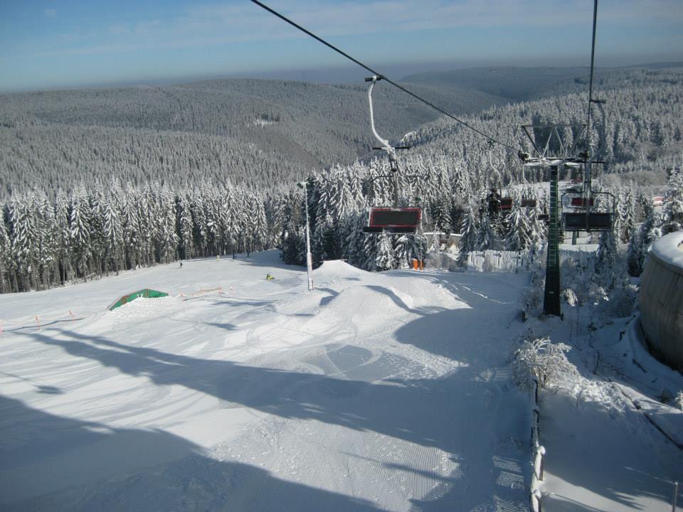 Blick vom Sessellift auf den verschneiten Fallbachhang in Oberhof mit Snowpark und Thüringer Wald
